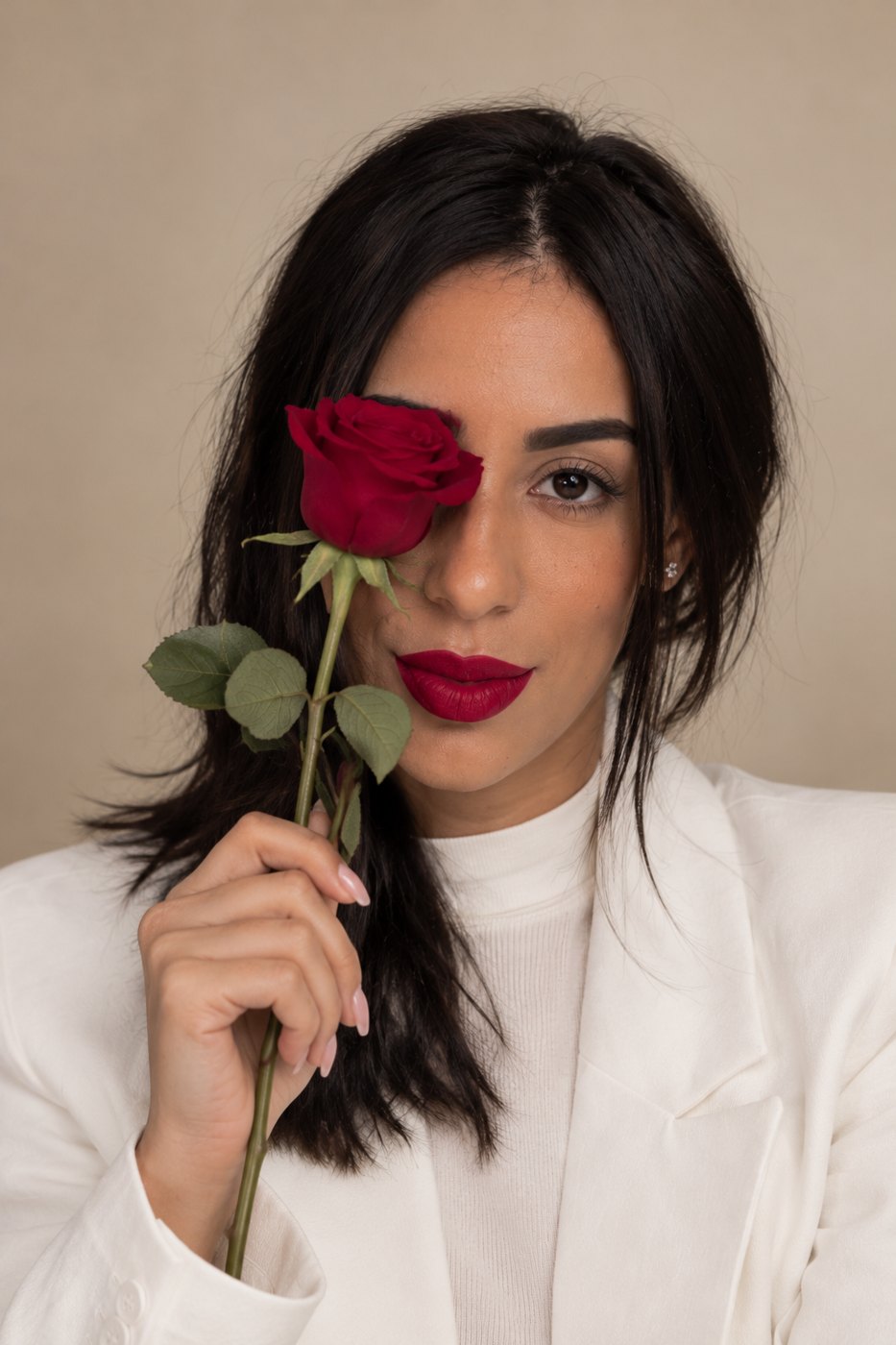 Thaís Rosa segurando uma rosa vermelha diante do rosto